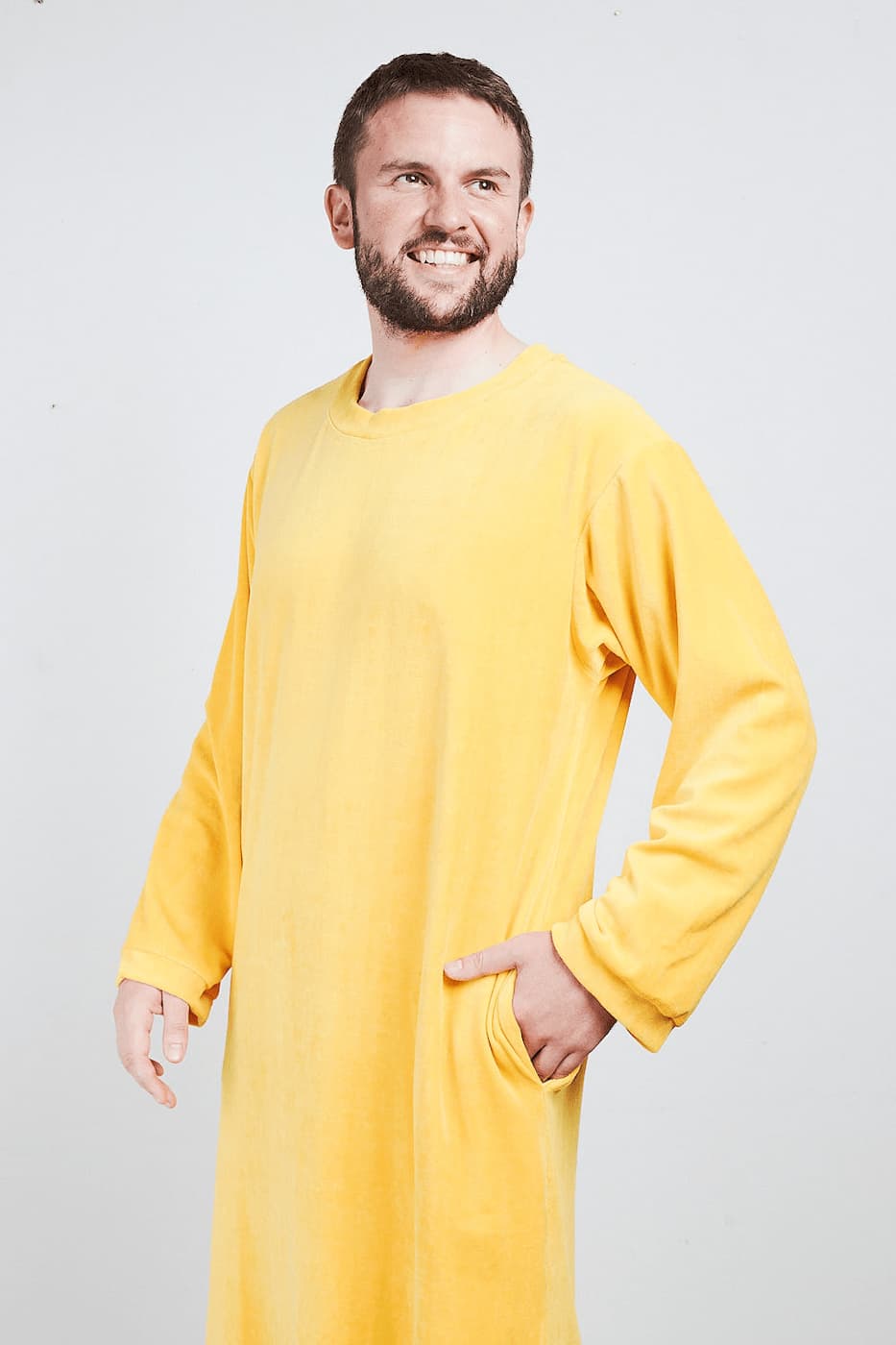 Mann im gelben Sonus Aeris Nicki-Velours Einteiler mit Taschen vor hellem Hintergrund