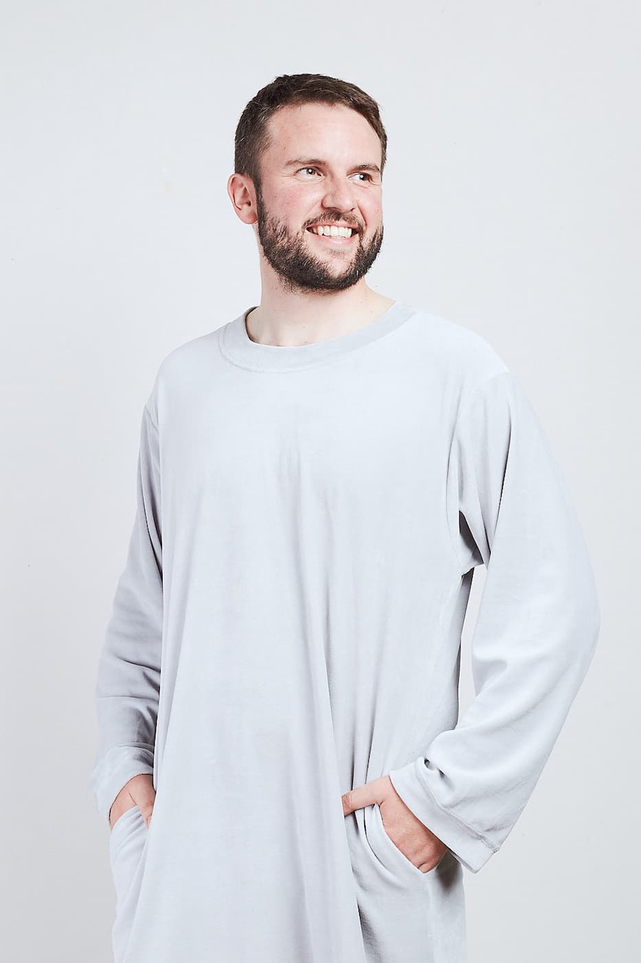 Mann im hellgrauen Sonus Aeris Nicki-Velours Einteiler mit Taschen vor hellem Hintergrund