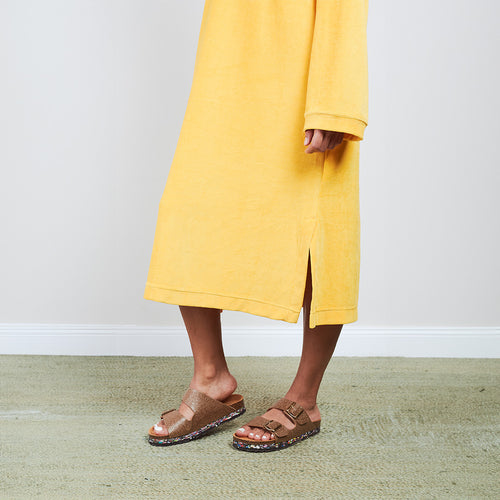Detail shot of gold ochre Sonus Aeris one-piece with side slit and sandals