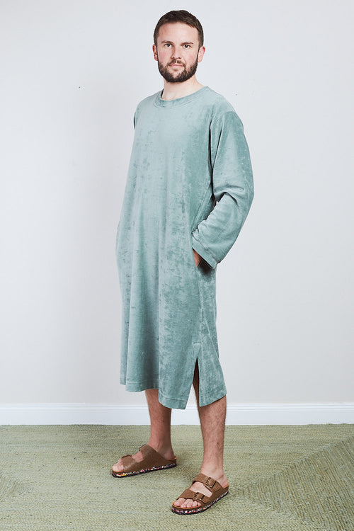 Man in sage green Sonus Aeris one-piece with pockets against light background