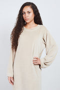 Woman in taupe Sonus Aeris one-piece against light background
